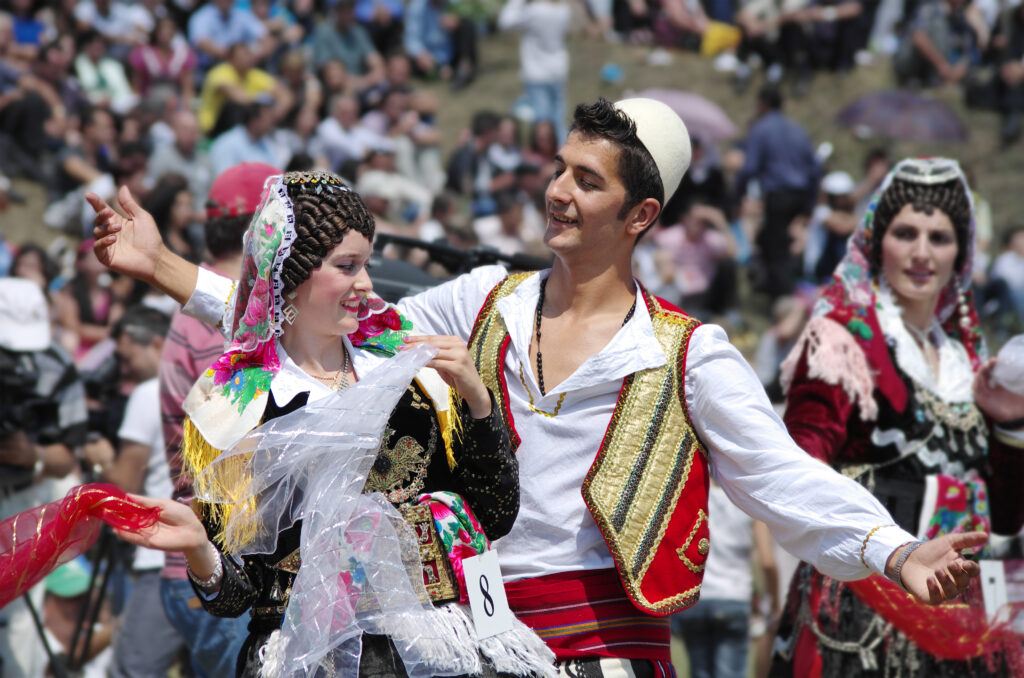 Een jong stel in Albanees kleding voert een baltsdans uit.