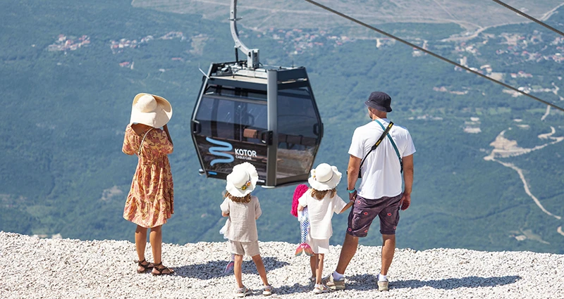 Vader, moeder en kinderen kijken uit op kabelbaan van Kotor